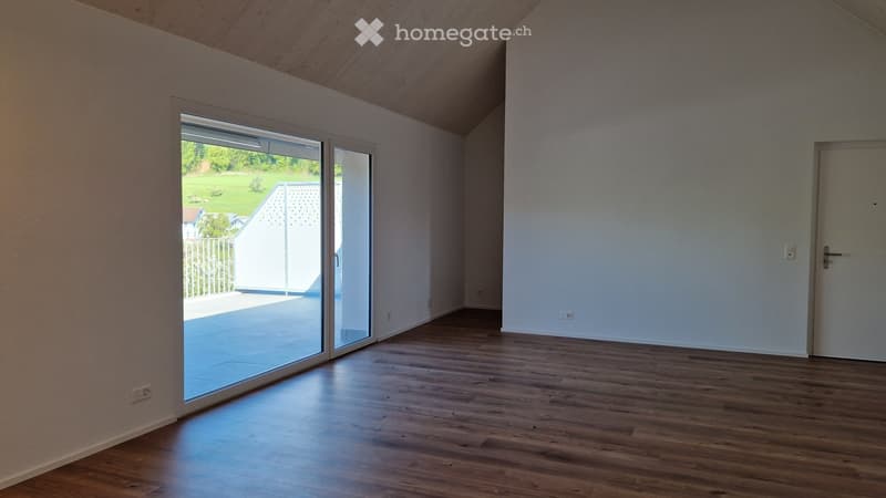Empty room with wooden flooring, large sliding glass door leading to outdoor area, white walls, and visible electrical outlets.