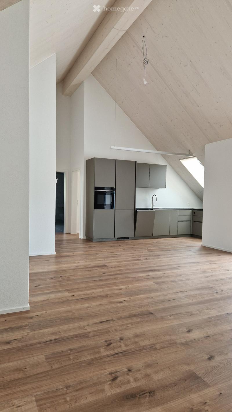 Modern kitchen with wooden flooring, grey cabinets, and stainless steel appliances including a refrigerator and sink.