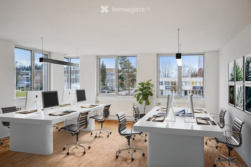 modern office with white desks, black office chairs, monitors, and large windows