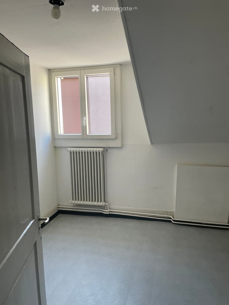 Empty room with white walls, ceiling, and floor, a window, and a radiator