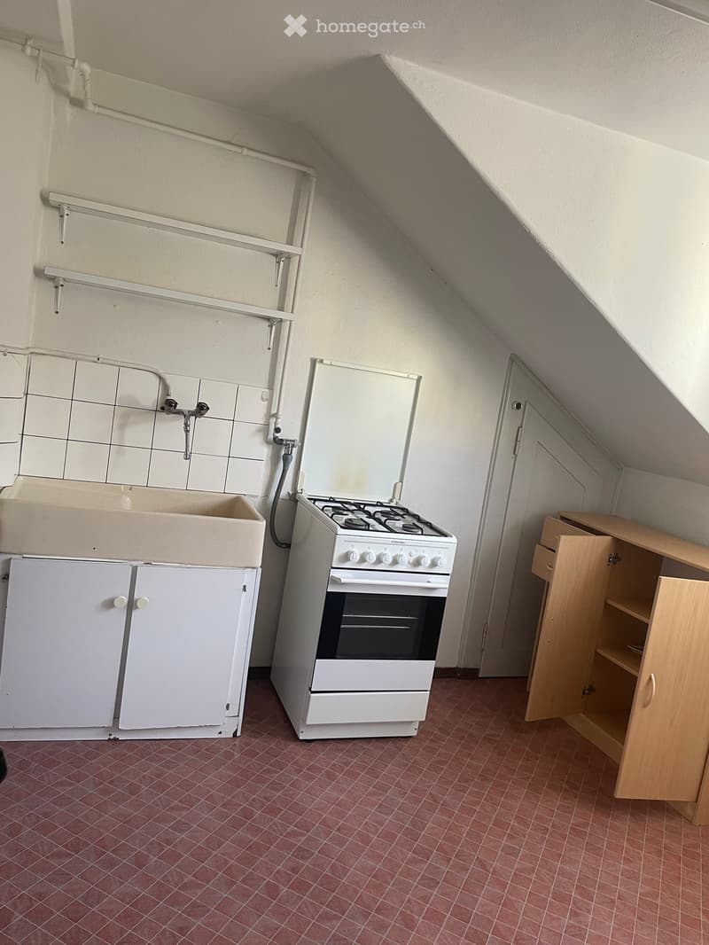 small kitchen with sink, gas stove, oven, cabinets, red tiles