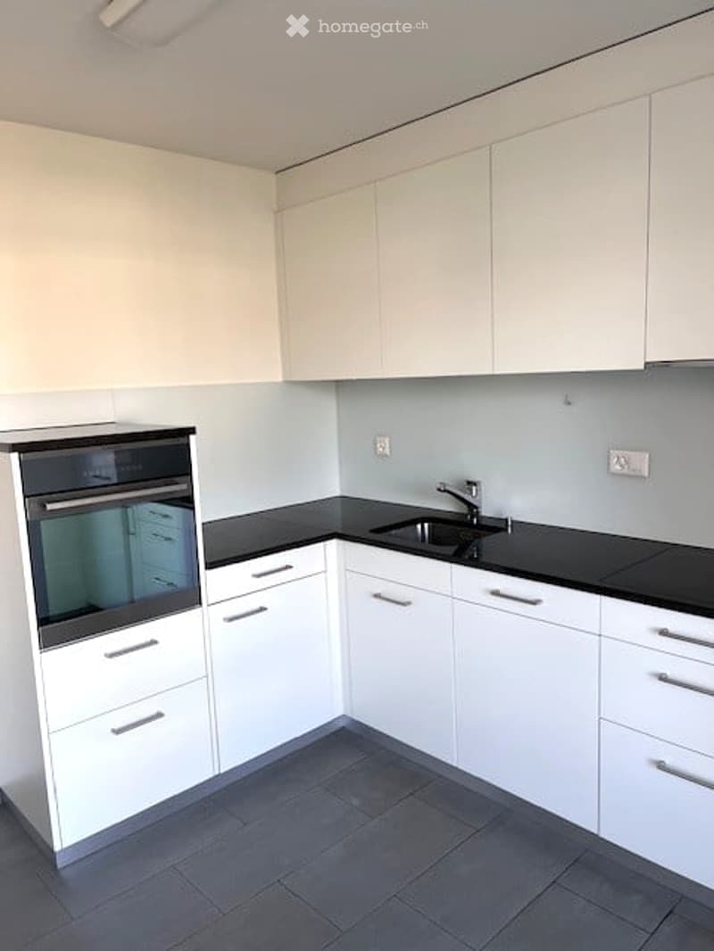 Modern kitchen with white cabinets, black countertops, and a built-in oven. Features a sleek sink with a modern faucet.