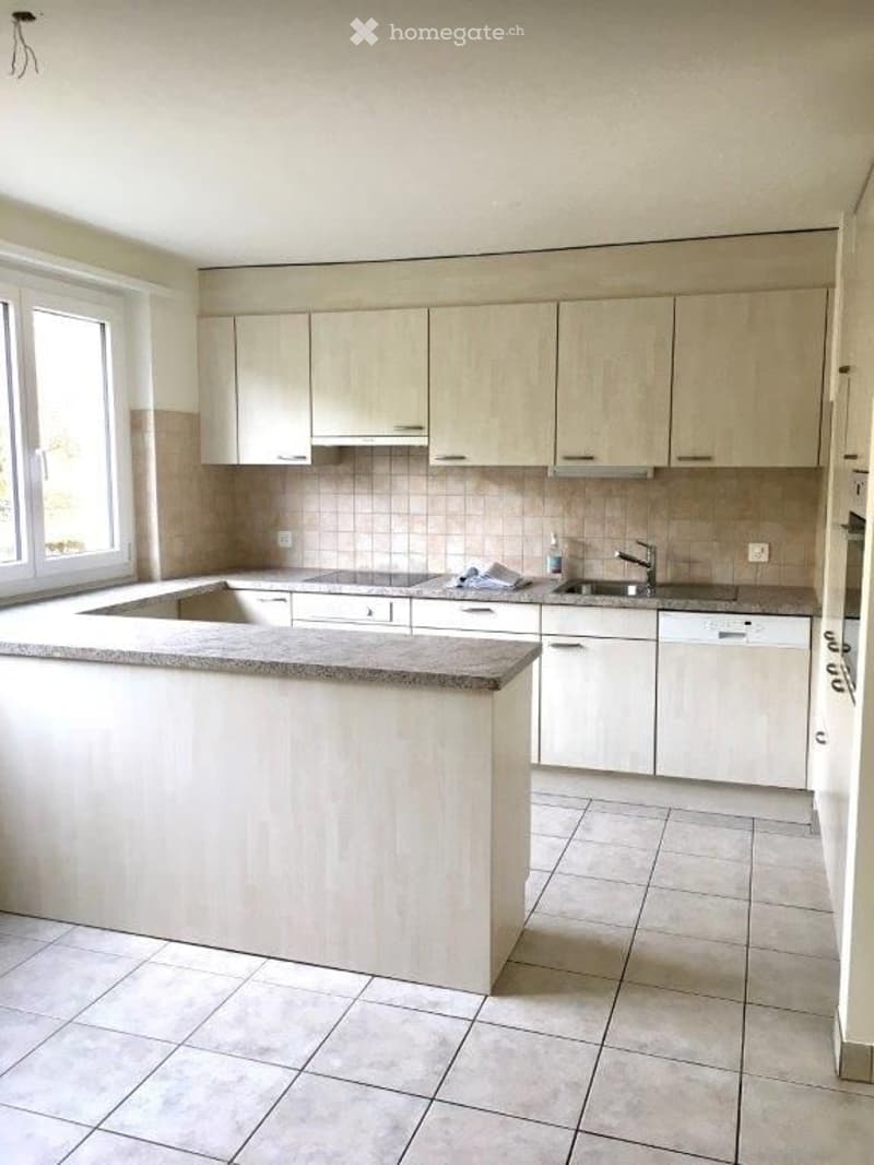Modern kitchen with white cabinets, a central island, and a tiled floor. Features include a sink, faucet, and a dishwasher.