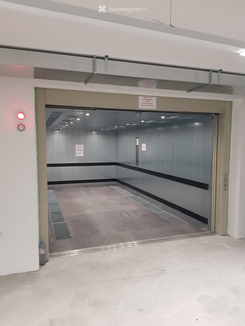 Empty hallway with a closed elevator door, white walls, and a concrete floor.