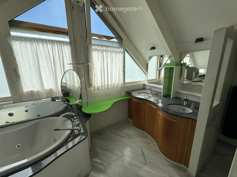 Modern bathroom with a large bathtub, double sink, mirrored cabinets, and ample natural light from skylights.