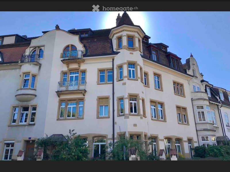 A multi-story residential building with a classic architectural style, featuring arched windows, balconies, and a decorative roofline.