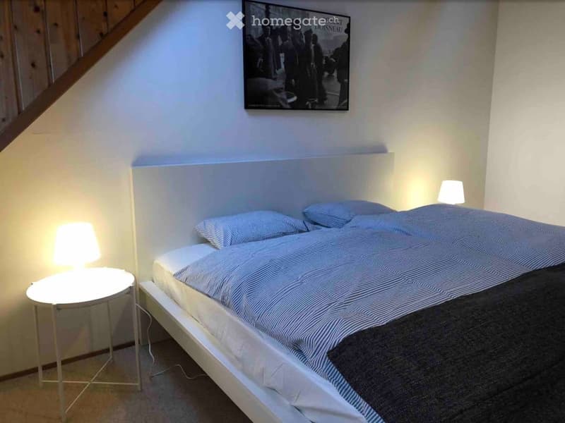 Modern bedroom with a white bed, blue and white striped bedding, two nightstands with lamps, and a large framed poster on the wall.