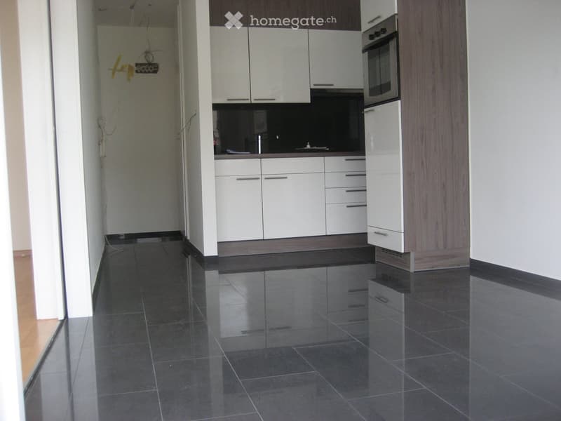 Modern kitchen with white cabinets, dark tiled floor, and built-in oven.