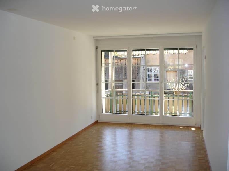 empty room, white walls, wooden floor, large glass doors leading to balcony