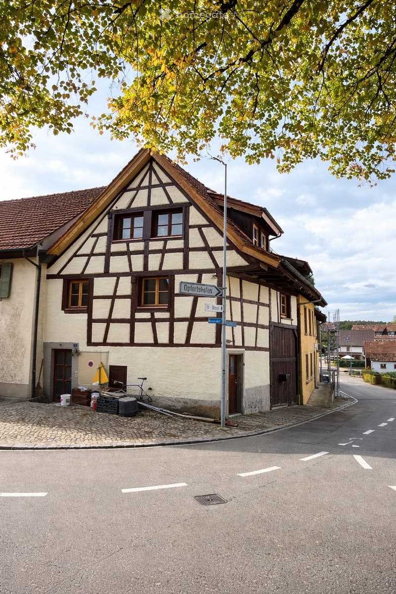 Traditional house with wooden and brick walls, brown roof, small porch, bicycles parked outside