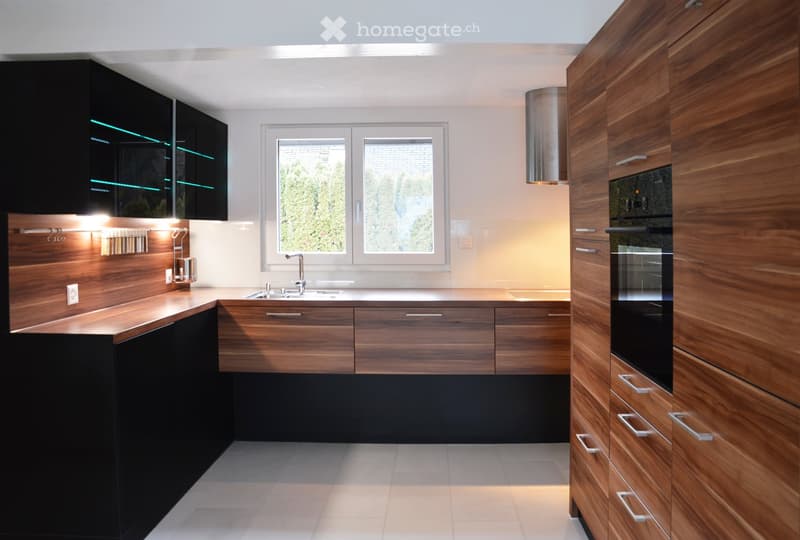 Modern kitchen with wooden and black cabinets, stainless steel sink, and built-in oven.