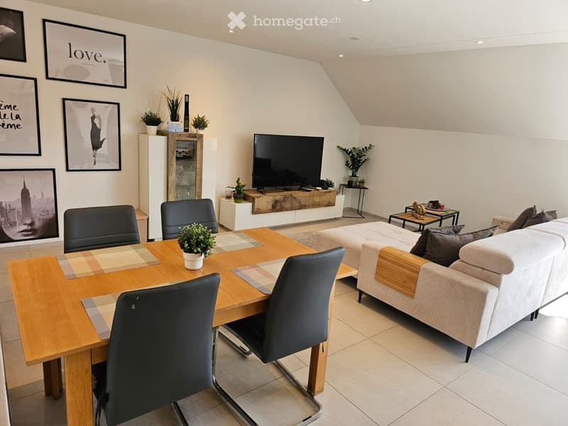 Modern living room with a white sofa, coffee table, dining table with chairs, television, and decorative plants.