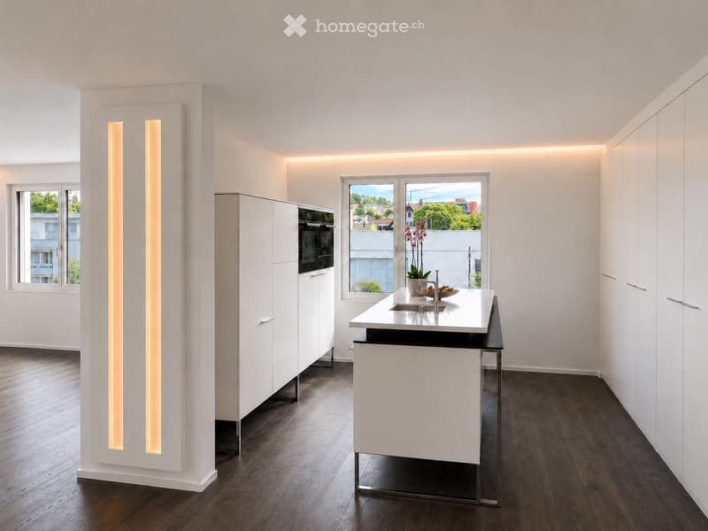 Modern kitchen with white cabinets, a central island, and a sleek countertop. Features include built-in lighting, a sink, and a vase with flowers on the island.