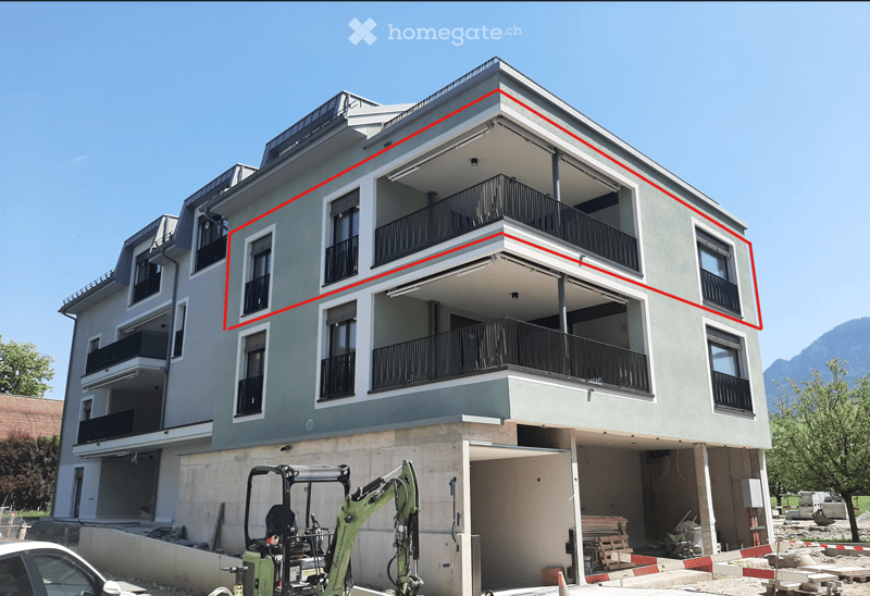 Modern multi-story residential building with balconies and a visible garage entrance.