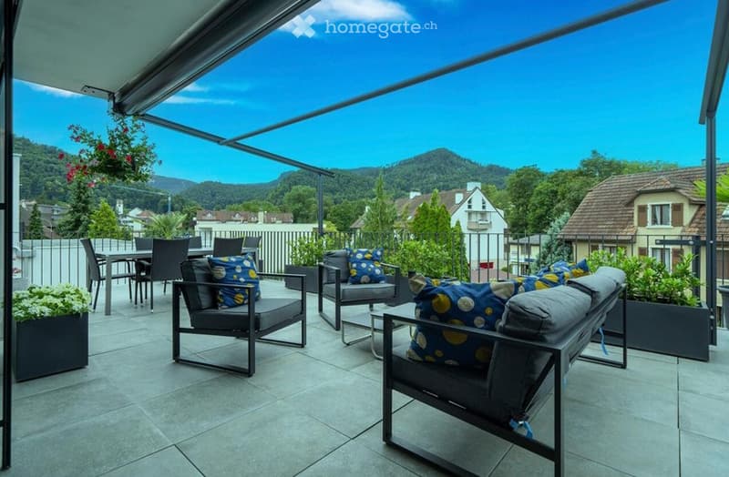 Balcony with outdoor furniture, including chairs, a sofa, and a coffee table, overlooking a scenic mountain view.