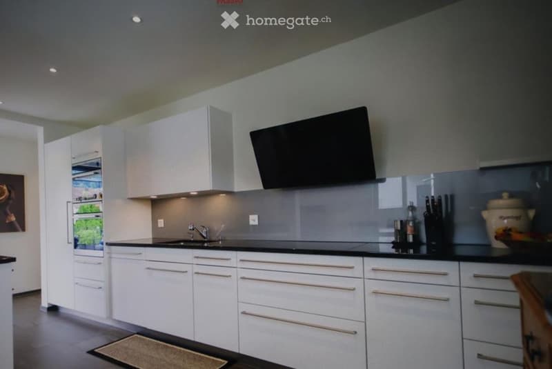 Modern kitchen with white cabinets, stainless steel appliances, and a sleek black countertop.