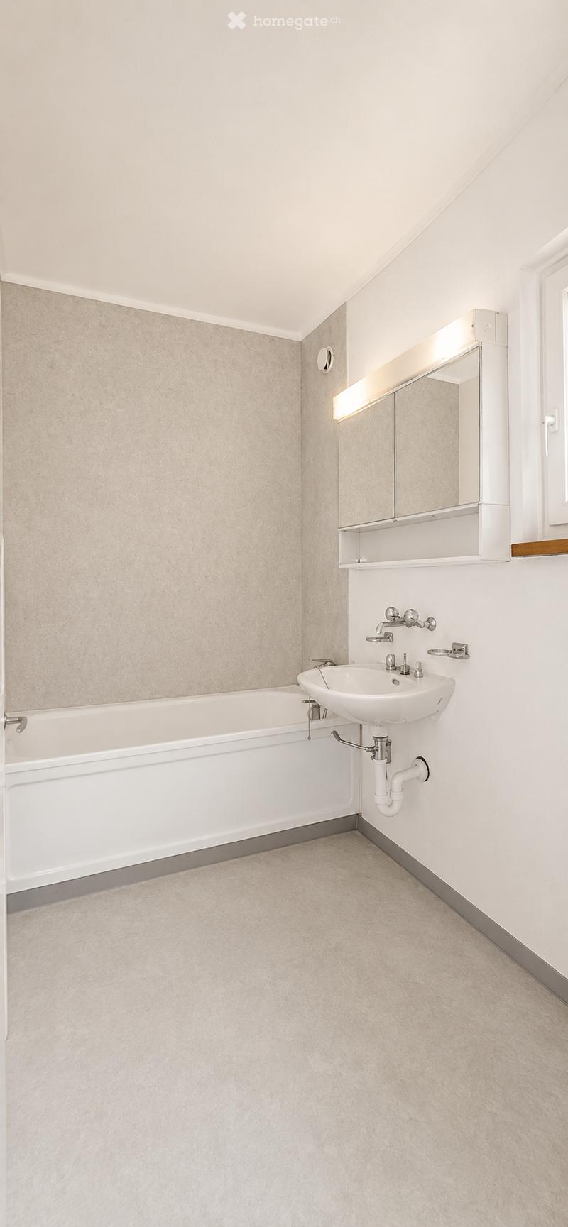 Modern bathroom with a white bathtub, a white sink, a large mirror with built-in lighting, and a sleek faucet.