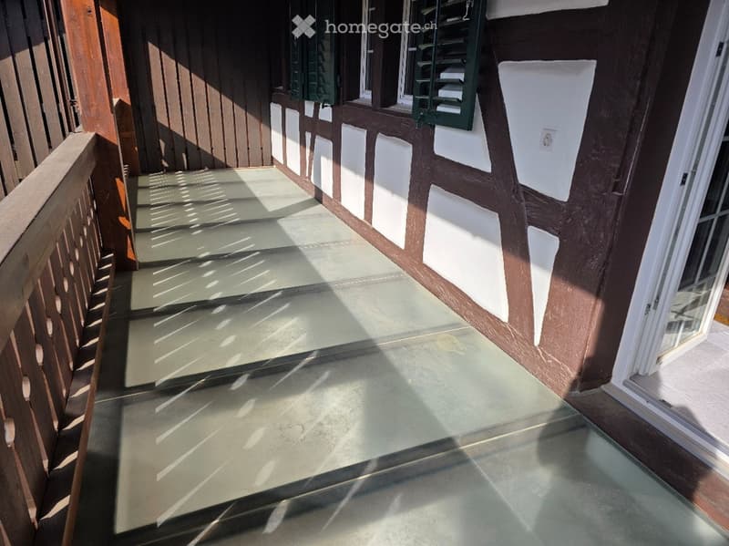 Balcony with wooden railing, glass floor, and traditional half-timbered wall design.