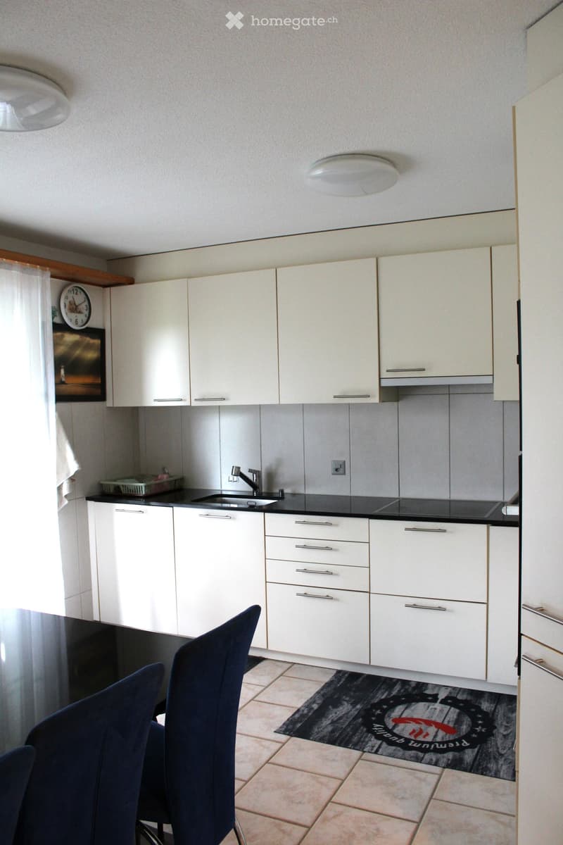 modern kitchen with white cabinets, black countertops, stainless steel sink, faucet, and appliances