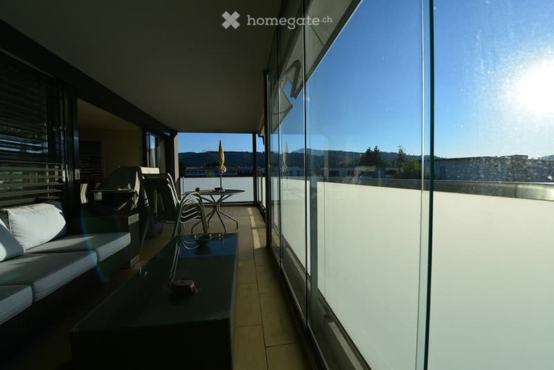 Balcony with a sofa, table, chairs, and an umbrella, offering a scenic mountain view.