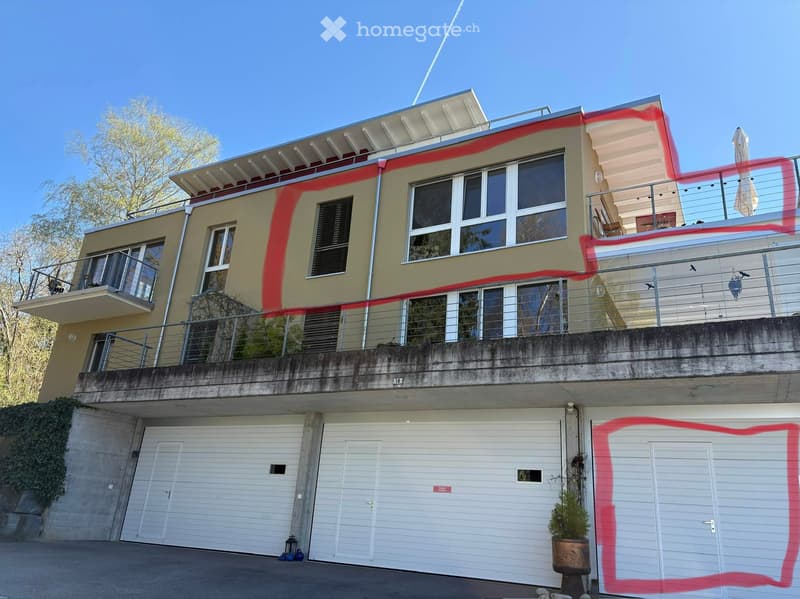 Two-story house with a modern design, featuring large windows, balconies, and a garage. The building has a light-colored facade with multiple levels and outdoor seating areas.