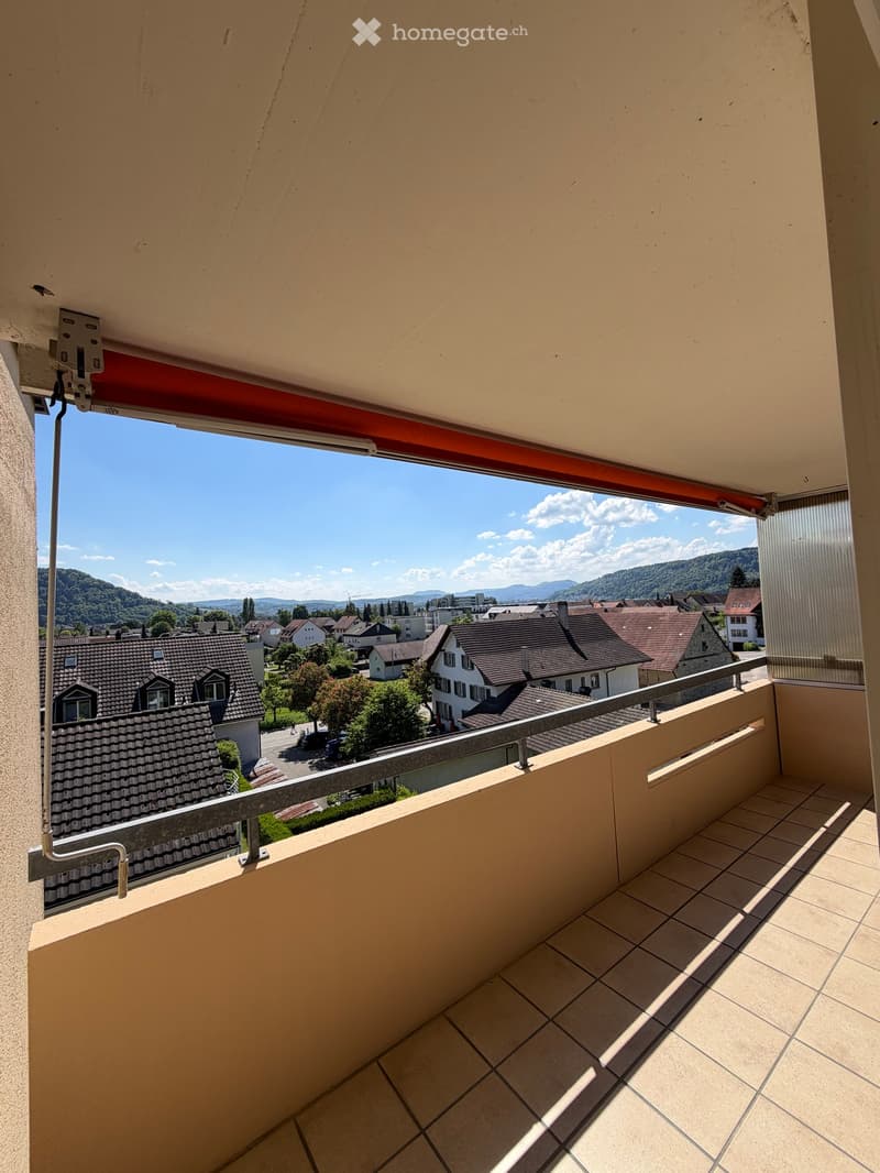 Balcony with tiled floor, metal railing, and scenic view of town and mountains.