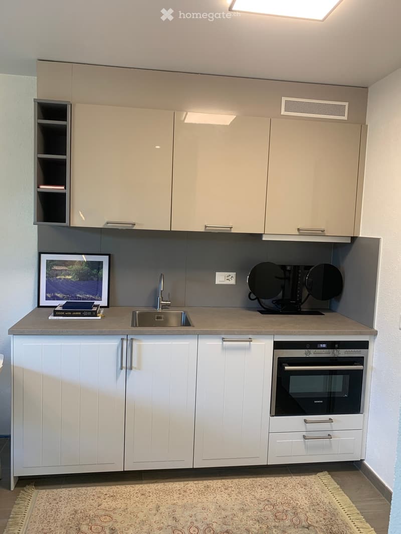 modern kitchen with white cabinets, granite countertop, stainless steel sink, built-in oven, dishwasher, and a framed picture on the wall