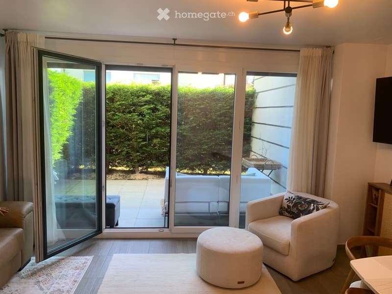 sliding glass doors, balcony, white couch, armchair, ottoman, rug, wooden floor, chandelier