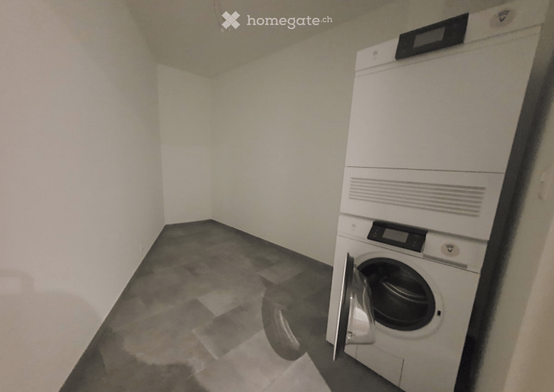 A small, unfurnished room with a washing machine, tiled floor, and white walls.