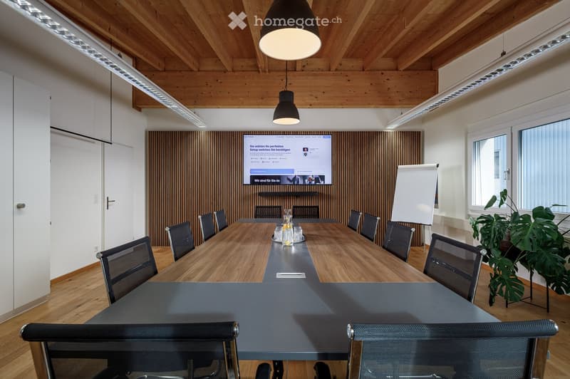 conference room with a long table, chairs, a whiteboard, a monitor, and a wooden wall