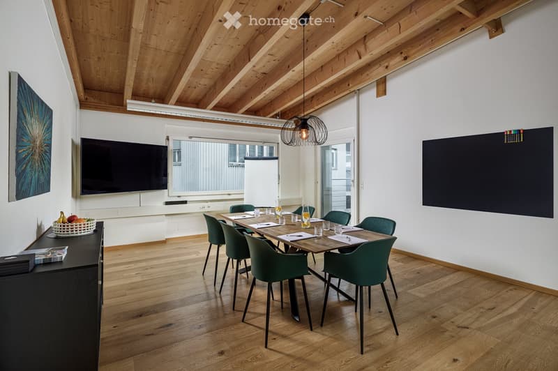 modern meeting room with wooden floor, wooden table, green chairs, TV, blackboard, artwork, and a basket of fruits
