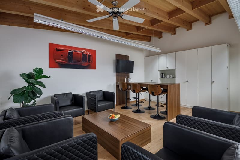 modern living room with black leather couches, wooden coffee table, wooden ceiling, white walls, wooden floor, kitchen area with bar stools, TV, and cabinets