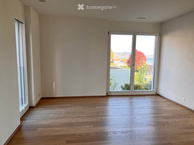 Empty room with wooden flooring, large sliding glass doors, and white walls.