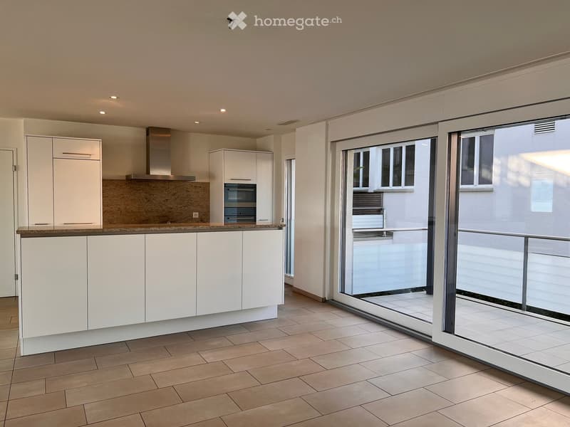Modern kitchen with white cabinets, a central island, and a large sliding glass door leading to a balcony.