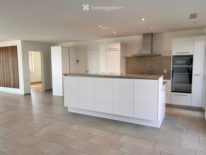 Modern kitchen with white cabinets, a central island, and built-in oven. Features tiled flooring and recessed lighting.