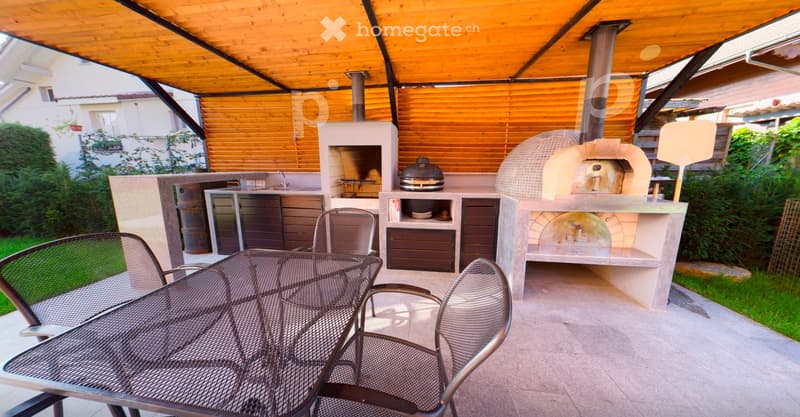 Outdoor patio with a wooden roof, a round wooden oven, a grill, a sink, and a dining area with a table and chairs.