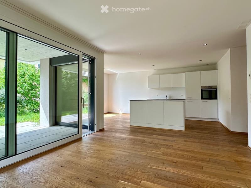 Modern, minimalist kitchen with white cabinets, a central island, and a large sliding glass door leading to a patio.