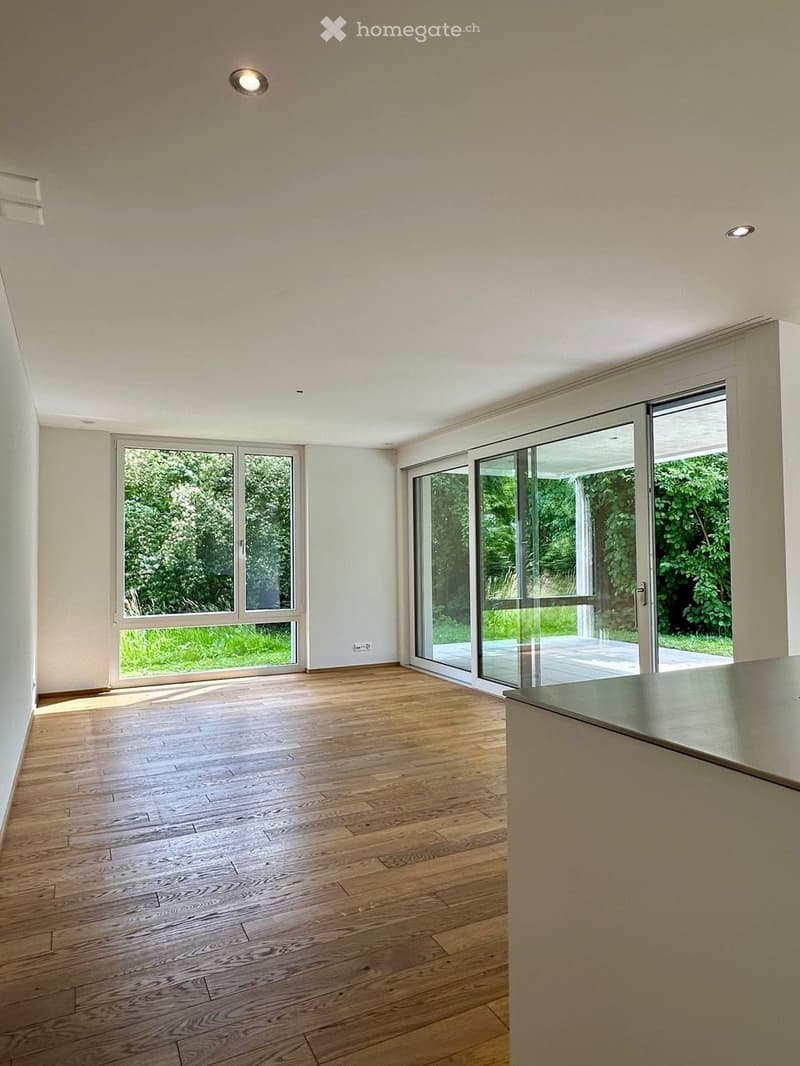 Empty room with wooden flooring, large windows, and recessed lighting. No furniture or equipment present.