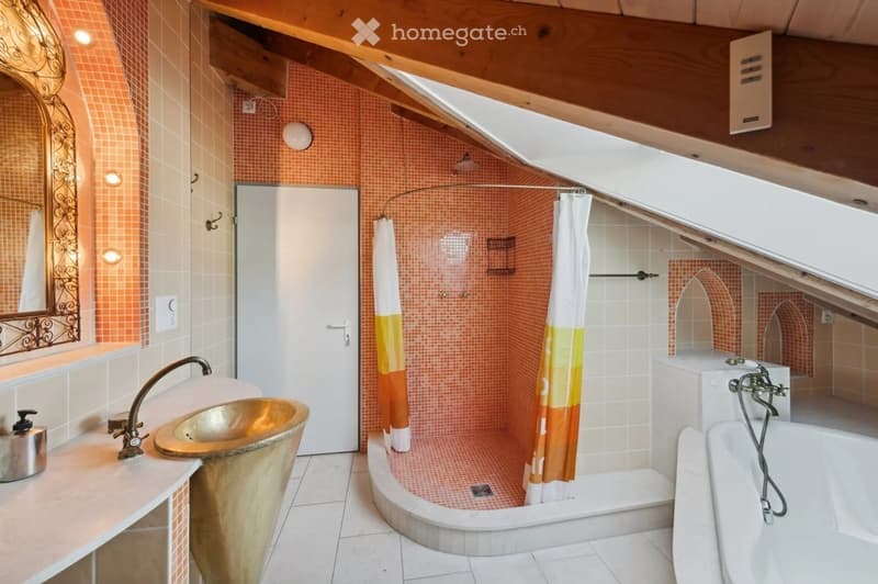 Bathroom with orange tiles, a unique copper sink, a bathtub, a shower stall with a colorful curtain, and a decorative mirror.