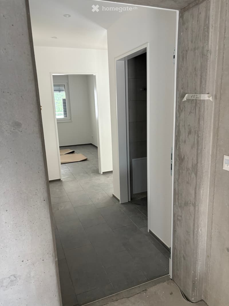 Empty hallway with tiled floor, white walls, and two open doors leading to other rooms.