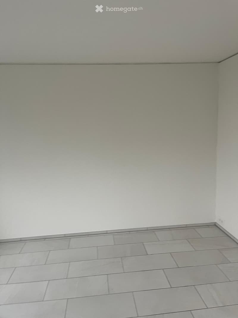 Empty room with light grey tiled floor and white walls, no furniture or equipment.