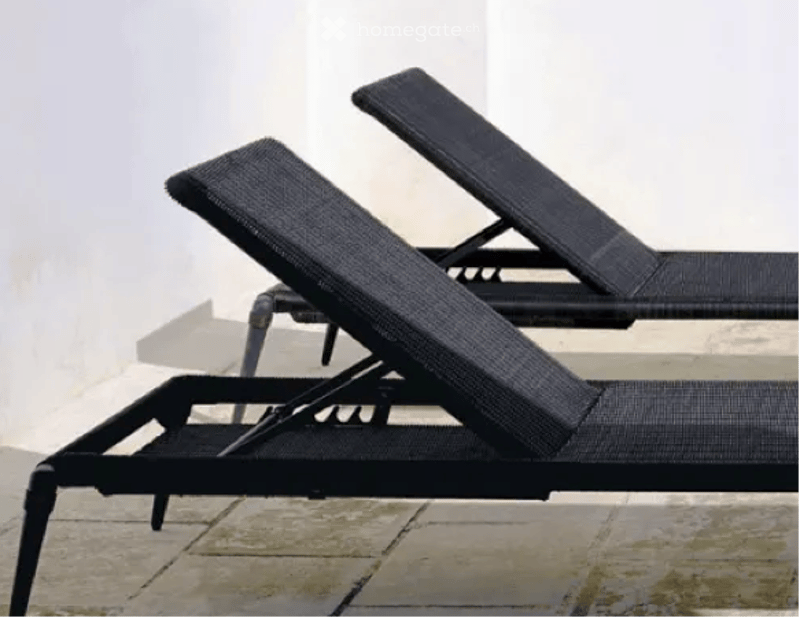 Two outdoor reclining loungers with black frames and mesh fabric on a terrace