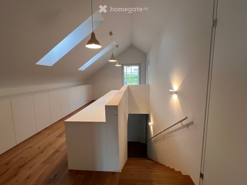 Corridor / Hallway. Modern, minimalist hallway with wooden flooring, white walls, built-in cabinets, pendant lights, and a staircase leading upwards.