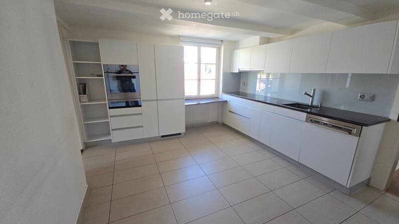 Modern kitchen with white cabinets, tiled floor, and built-in appliances including a dishwasher and sink.
