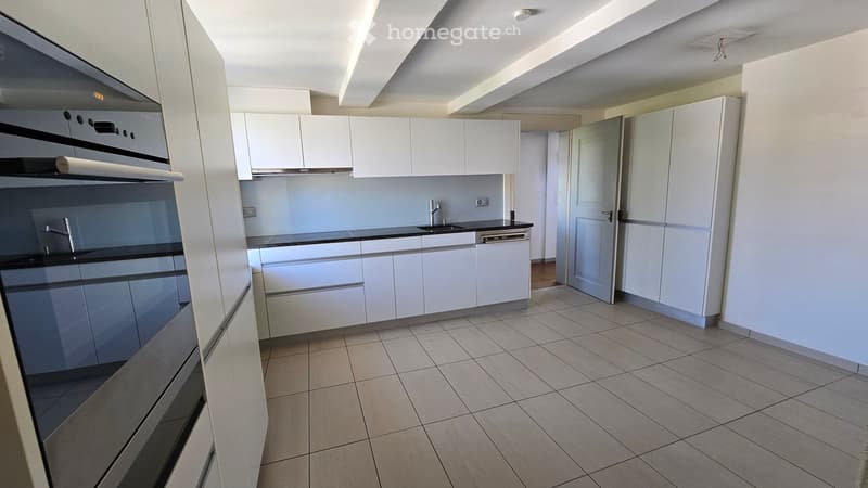 Modern kitchen with white cabinets, black countertops, and built-in appliances including an oven and dishwasher.