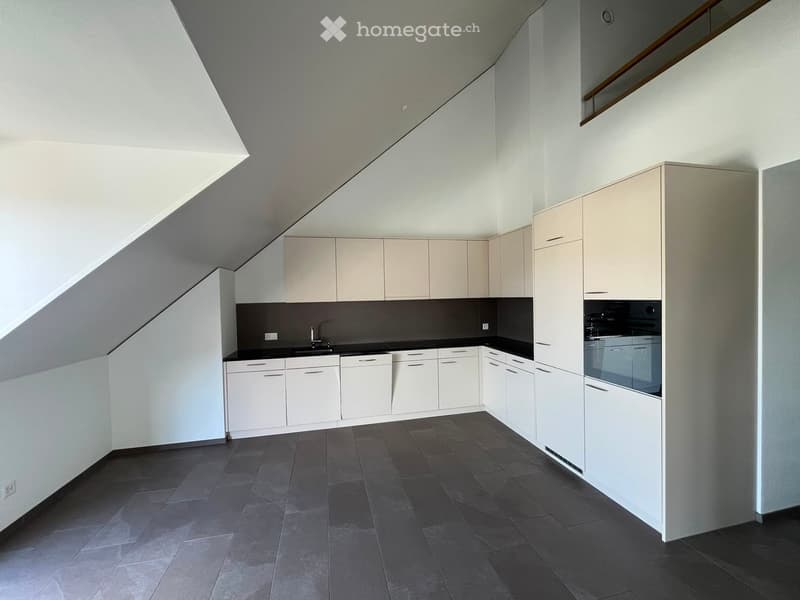 Modern kitchen with white cabinets, dark countertops, and dark tiled flooring. Features a sink, faucet, and built-in oven.