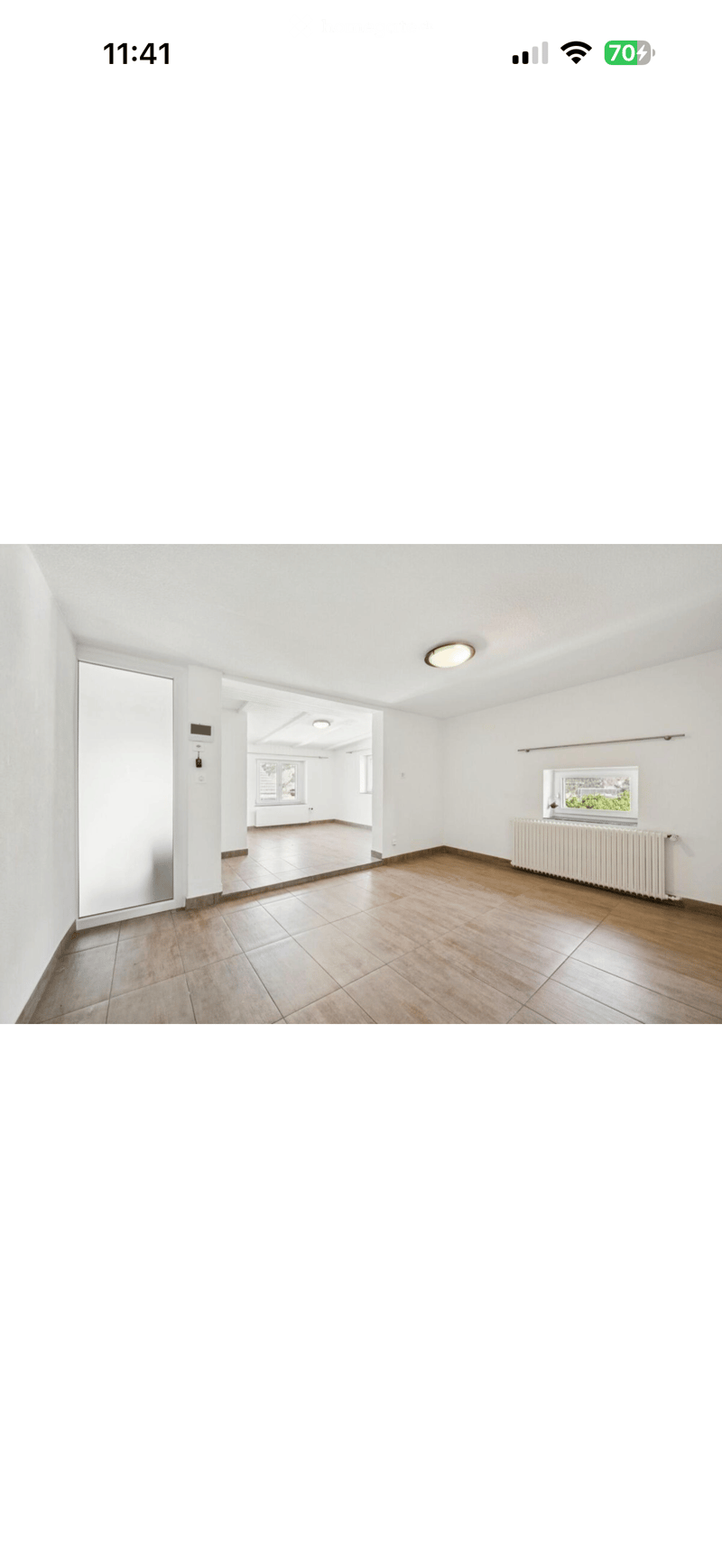 Empty room with white walls, wooden flooring, and large windows. No furniture or equipment visible.