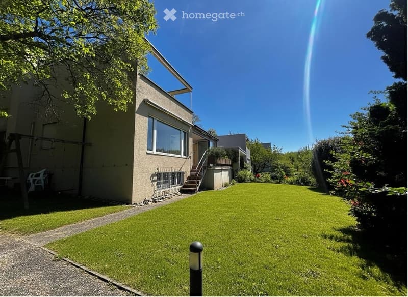 Modern house with a well-maintained garden, featuring a large lawn, a swing, and a pathway leading to the entrance.