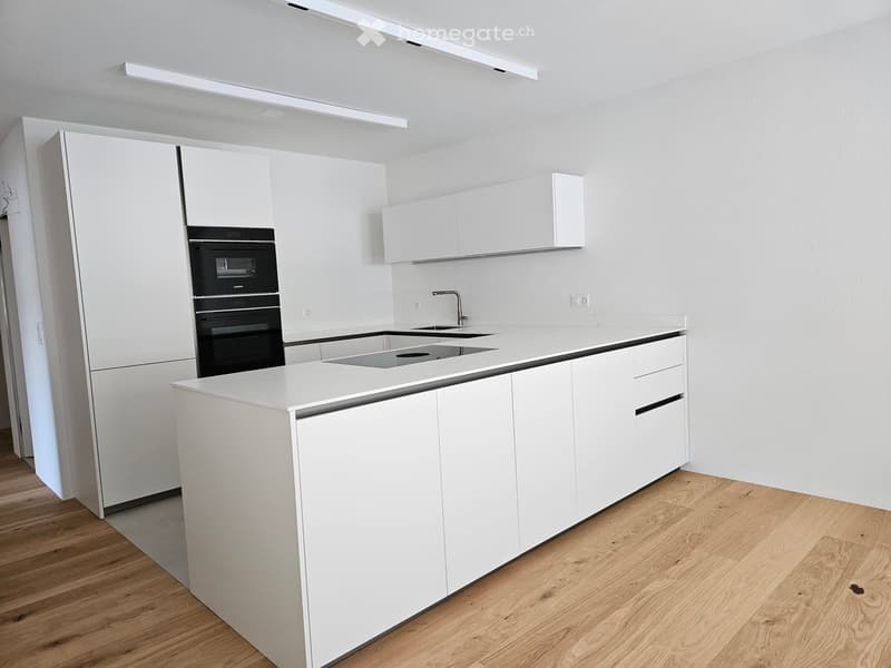 Modern kitchen, with white cabinets, countertops, hardwood floors, two ovens, and a sink with a faucet
