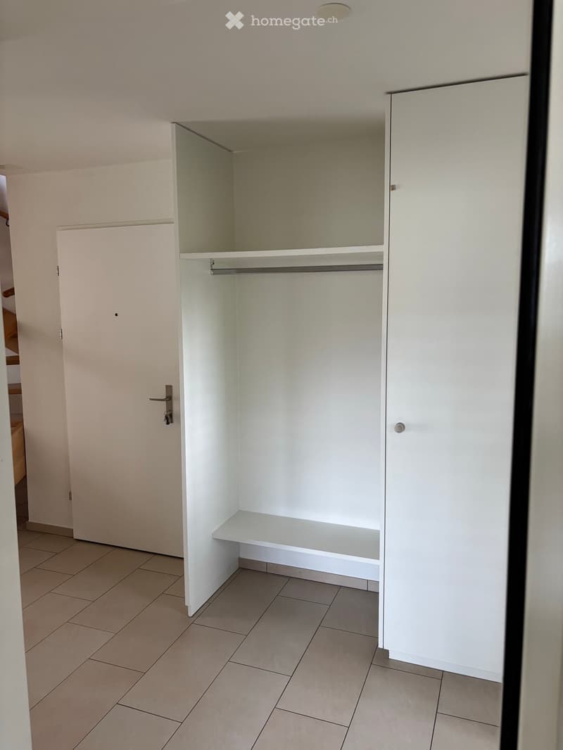 Empty closet with white walls, tiled floor, and built-in shelving and hanging space.